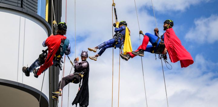 Técnicos especializados en acceso mediante cuerdas, vestidos de superhéroes, descienden en rápel por la fachada del Hospital Infantil del Hospital Universitario de Lausana (CHUV) para conmemorar el primer aniversario del nuevo edificio en Lausana.