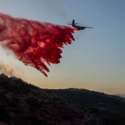 Un avión de Cal Fire arroja retardante de fuego sobre el incendio Sandy mientras arde en las colinas cerca de una zona residencial en Simi Valley, California. Un incendio forestal se desató en los suburbios de Los Ángeles, propagándose rápidamente y obligando a las autoridades a emitir órdenes de evacuación para miles de residentes. | Foto:APU GOMES / AFP