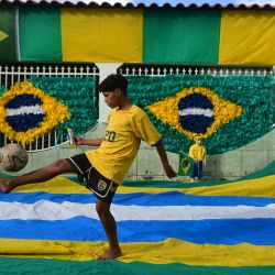 Un niño controla la pelota frente a una casa decorada con motivos de la bandera nacional brasileña en preparación para la Copa Mundial de la FIFA 2026, en Brasilia, Brasil. | Foto:Xinhua/Lucio Tavora