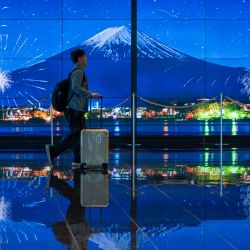 Un viajero pasa junto a una imagen del Monte Fuji en la terminal de llegadas del aeropuerto de Haneda en Tokio, Japón. | Foto:Kazuhiro Nogi / AFP