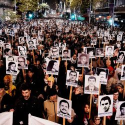 Fotografía difundida por la agencia de noticias adhoc que muestra a personas sosteniendo retratos de quienes desaparecieron durante la última dictadura en Uruguay mientras participan en la Marcha del Silencio en Montevideo. | Foto:Javier Calvelo / adhoc / AFP
