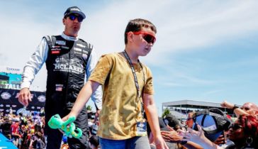 Kyle Busch, izquierda, y su hijo, saludan a los fanáticos previo a una carrera de la NASCAR Cup Series en Talladega Superspeedway, el 23 de abril de 2023, en Talladega, Alabama 
