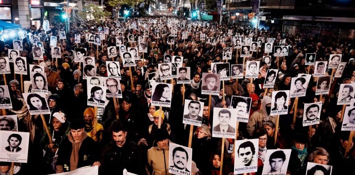 Fotografía difundida por la agencia de noticias adhoc que muestra a personas sosteniendo retratos de quienes desaparecieron durante la última dictadura en Uruguay mientras participan en la Marcha del Silencio en Montevideo.