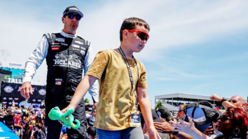 Kyle Busch, izquierda, y su hijo, saludan a los fanáticos previo a una carrera de la NASCAR Cup Series en Talladega Superspeedway, el 23 de abril de 2023, en Talladega, Alabama 