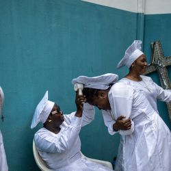 Un fiel usa un abanico sobre la cabeza de otra persona dentro del recinto de la sede internacional de la Iglesia Celestial de Cristo en el barrio de Ketu, en Lagos. | Foto:OLYMPIA DE MAISMONT / AFP