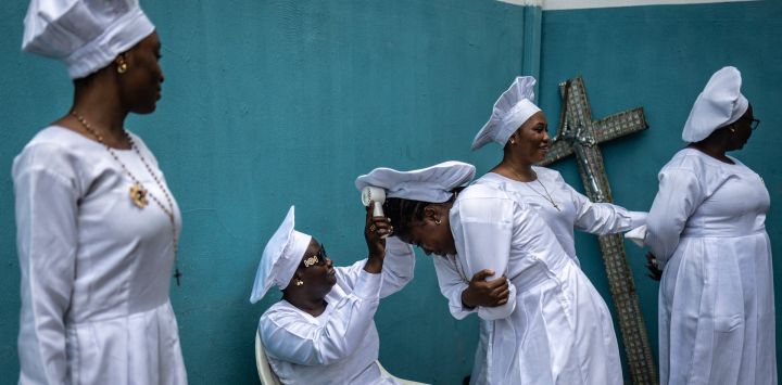 Un fiel usa un abanico sobre la cabeza de otra persona dentro del recinto de la sede internacional de la Iglesia Celestial de Cristo en el barrio de Ketu, en Lagos.