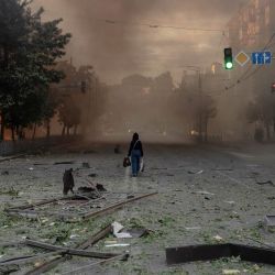 Una mujer camina por una calle llena de humo junto a edificios gravemente dañados tras los ataques rusos en Kiev, en el contexto de la invasión rusa de Ucrania. Un potente ataque con misiles balísticos sacudió Kiev, según informaron las autoridades, hiriendo al menos a cinco personas después de que Moscú amenazara con represalias por los ataques en el este de Ucrania, territorio ocupado por Rusia. | Foto:ROMAN PILIPEY / AFP