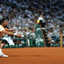 El serbio Novak Djokovic devuelve un golpe de derecha al francés Giovanni Mpetshi Perricard durante su partido individual masculino en la primera jornada del torneo de tenis Roland Garros, disputado en la pista Philippe-Chatrier del complejo Roland-Garros en París. | Foto:Thomas Samson / AFP