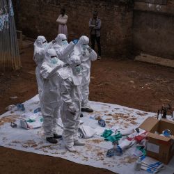 Trabajadores de la Cruz Roja de Uganda se visten con trajes de protección mientras se preparan para evacuar el cuerpo de una presunta víctima de ébola en Kampala. La organización está preparada para ayudar al Ministerio de Salud a trasladar los casos sospechosos a centros de tratamiento y a realizar entierros seguros y dignos tras la confirmación de los resultados positivos. Esta acción se produce después de la confirmación de tres casos adicionales de ébola en Bundibugyo, lo que eleva el total a cinco vinculados a viajeros procedentes de la vecina República Democrática del Congo (RDC), donde un brote ha cobrado 119 vidas entre 904 casos sospechosos. La Organización Mundial de la Salud ha clasificado este brote, tanto en la RDC como en Uganda, como una emergencia de salud pública de importancia internacional. | Foto:BADRU KATUMBA / AFP