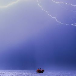 Un rayo cae durante una tormenta eléctrica mientras los miembros de la tripulación del buque de rescate "Ocean Viking", operado por la ONG francesa SOS Mediterranée, participan en un ejercicio nocturno de equipo para prepararse para una situación de rescate en el mar con una lancha neumática semirrígida (RHIB), en su camino hacia la zona de búsqueda y rescate en aguas internacionales del mar Mediterráneo. | Foto:SAMEER Al-DOUMY / AFP