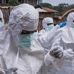 Trabajadores de la Cruz Roja de Uganda se visten con trajes de protección mientras se preparan para evacuar el cuerpo de una presunta víctima de ébola en Kampala. La organización está preparada para ayudar al Ministerio de Salud a trasladar los casos sospechosos a centros de tratamiento y a realizar entierros seguros y dignos tras la confirmación de los resultados positivos. Esta acción se produce después de la confirmación de tres casos adicionales de ébola en Bundibugyo, lo que eleva el total a cinco vinculados a viajeros procedentes de la vecina República Democrática del Congo (RDC), donde un brote ha cobrado 119 vidas entre 904 casos sospechosos. | Foto:BADRU KATUMBA / AFP