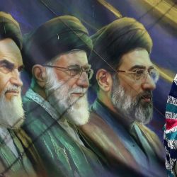 Una mujer iraní pasa junto a una pancarta con retratos del difunto fundador de la República Islámica, el ayatolá Ruhollah Khomeini (izquierda), el exlíder supremo ayatolá Ali Khamenei (centro), asesinado en febrero de 2026, y el actual líder supremo Mojtaba Khamenei (derecha), en Teherán, Irán. | Foto:AFP