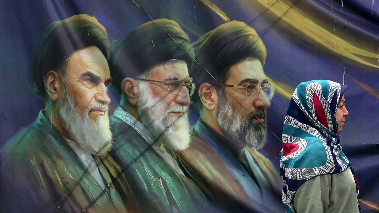 Una mujer iraní pasa junto a una pancarta con retratos del difunto fundador de la República Islámica, el ayatolá Ruhollah Khomeini (izquierda), el exlíder supremo ayatolá Ali Khamenei (centro), asesinado en febrero de 2026, y el actual líder supremo Mojtaba Khamenei (derecha), en Teherán, Irán. | Foto:AFP