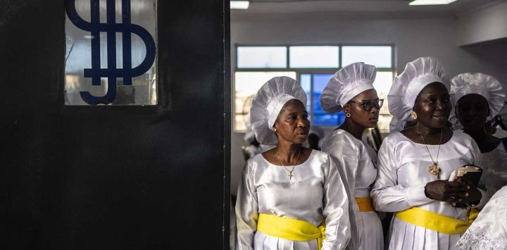 Los fieles permanecen de pie cerca de la puerta de salida durante un servicio religioso en la sede internacional de la Iglesia Celestial de Cristo en el barrio de Ketu, en Lagos, Nigeria.