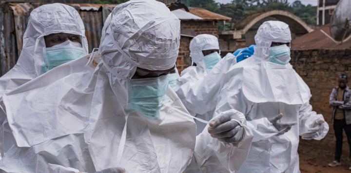 Trabajadores de la Cruz Roja de Uganda se visten con trajes de protección mientras se preparan para evacuar el cuerpo de una presunta víctima de ébola en Kampala. La organización está preparada para ayudar al Ministerio de Salud a trasladar los casos sospechosos a centros de tratamiento y a realizar entierros seguros y dignos tras la confirmación de los resultados positivos. Esta acción se produce después de la confirmación de tres casos adicionales de ébola en Bundibugyo, lo que eleva el total a cinco vinculados a viajeros procedentes de la vecina República Democrática del Congo (RDC), donde un brote ha cobrado 119 vidas entre 904 casos sospechosos.