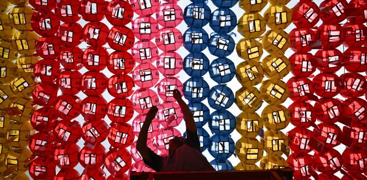 Un hombre coloca tarjetas con los deseos de los fieles budistas en faroles de loto expuestos en el templo Jogye tras una ceremonia para celebrar el cumpleaños de Buda en Seúl, Corea del Sur.