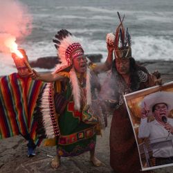 Chamanes sostienen un cartel del candidato presidencial Roberto Sánchez mientras realizan un ritual para predecir el ganador de la segunda vuelta electoral peruana en la playa de La Herradura, Lima. Perú celebrará la segunda vuelta electoral presidencial el 7 de junio. | Foto:ERNESTO BENAVIDES / AFP