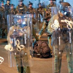 Un manifestante (no visible en la imagen) es arrestado mientras la policía estatal de Nueva Jersey monta guardia cerca de Delaney Hall, un centro de detención del Servicio de Inmigración y Control de Aduanas (ICE), durante el toque de queda en Newark, Nueva Jersey. | Foto:EDUARDO MUNOZ / AFP