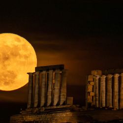 La luna llena se eleva tras el antiguo templo griego de Poseidón en el cabo Sunión, a unos 60 kilómetros al sur de Atenas, Grecia. | Foto:ARIS MESSINIS / AFP