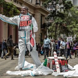 Un activista grita consignas a los transeúntes junto a un ataúd simbólico durante una protesta contra un centro de cuarentena para el ébola construido por Estados Unidos, cuya apertura estaba prevista en la base aérea de Laikipia, en Kenia, en el centro de Nairobi. El presidente de Kenia defendió la apertura de un centro de cuarentena para ciudadanos estadounidenses después de que un tribunal paralizara el plan y las fuerzas de seguridad lanzaran gases lacrimógenos contra los manifestantes que temían que el virus mortal se propagara en el país. Según funcionarios estadounidenses, las instalaciones construidas por Estados Unidos en la base aérea de Laikipia debían abrir la semana pasada para poner en cuarentena a los estadounidenses que llegaran de la República Democrática del Congo (RDC), que lucha contra un importante brote de ébola. | Foto:LUIS TATO / AFP