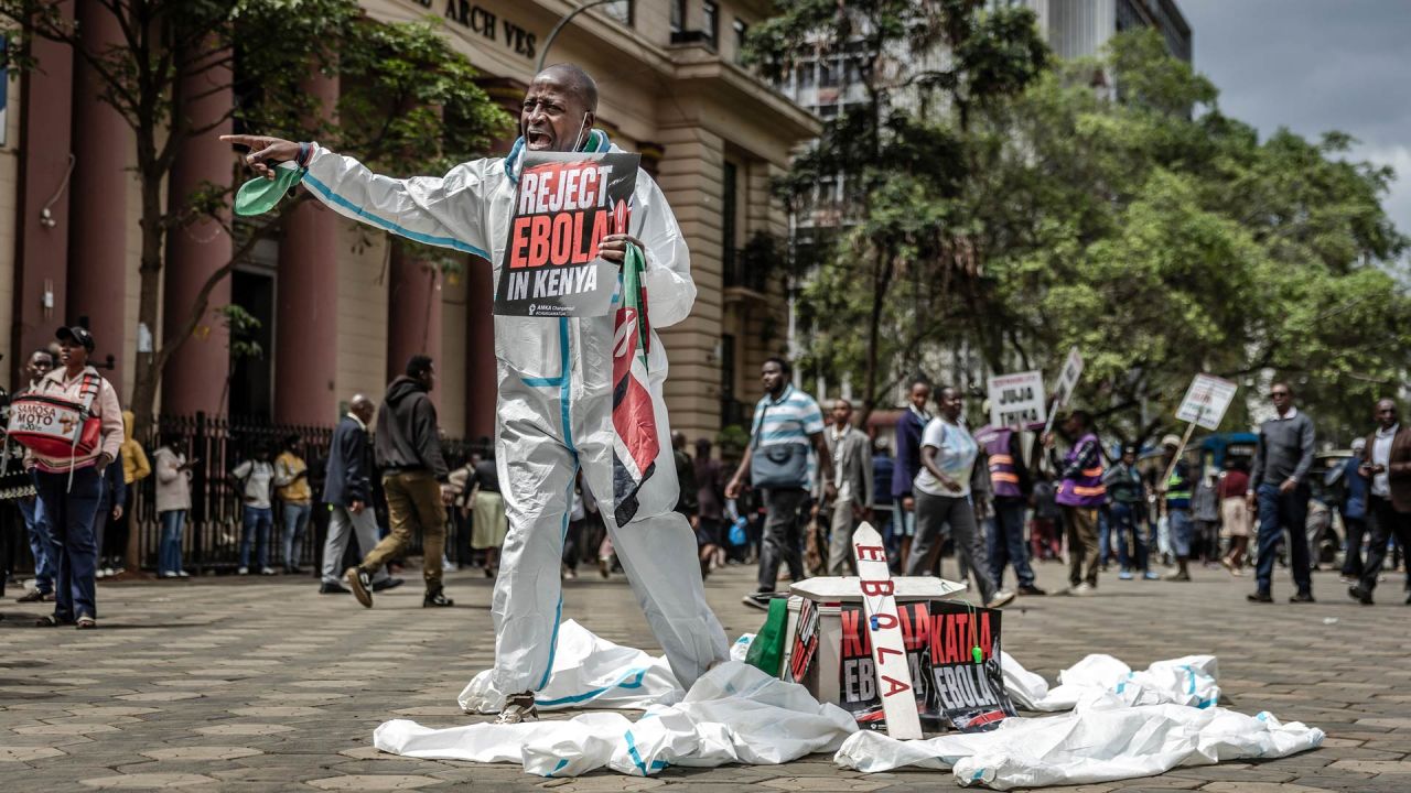 Un activista grita consignas a los transeúntes junto a un ataúd simbólico durante una protesta contra un centro de cuarentena para el ébola construido por Estados Unidos, cuya apertura estaba prevista en la base aérea de Laikipia, en Kenia, en el centro de Nairobi. El presidente de Kenia defendió la apertura de un centro de cuarentena para ciudadanos estadounidenses después de que un tribunal paralizara el plan y las fuerzas de seguridad lanzaran gases lacrimógenos contra los manifestantes que temían que el virus mortal se propagara en el país. Según funcionarios estadounidenses, las instalaciones construidas por Estados Unidos en la base aérea de Laikipia debían abrir la semana pasada para poner en cuarentena a los estadounidenses que llegaran de la República Democrática del Congo (RDC), que lucha contra un importante brote de ébola. | Foto:LUIS TATO / AFP