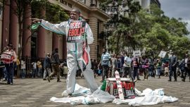 Un activista grita consignas a los transeúntes junto a un ataúd simbólico durante una protesta contra un centro de cuarentena para el ébola construido por Estados Unidos, cuya apertura estaba prevista en la base aérea de Laikipia, en Kenia, en el centro de Nairobi. El presidente de Kenia defendió la apertura de un centro de cuarentena para ciudadanos estadounidenses después de que un tribunal paralizara el plan y las fuerzas de seguridad lanzaran gases lacrimógenos contra los manifestantes que temían que el virus mortal se propagara en el país. Según funcionarios estadounidenses, las instalaciones construidas por Estados Unidos en la base aérea de Laikipia debían abrir la semana pasada para poner en cuarentena a los estadounidenses que llegaran de la República Democrática del Congo (RDC), que lucha contra un importante brote de ébola.