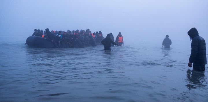 Traficantes de personas ayudan a migrantes a abordar una embarcación en un intento por cruzar el Canal de la Mancha frente a la playa de Gravelines, en el norte de Francia.
