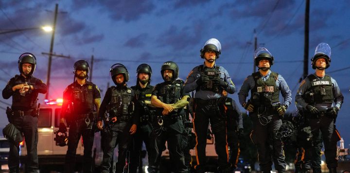 Agentes de la policía estatal de Nueva Jersey montan guardia cerca de Delaney Hall, centro de detención del Servicio de Inmigración y Control de Aduanas (ICE), minutos antes del inicio del toque de queda, en Newark, Nueva Jersey. Las autoridades estatales de Nueva Jersey anunciaron que se harían cargo de la seguridad en las inmediaciones del centro de detención de inmigrantes tras los enfrentamientos entre agentes del ICE y manifestantes indignados por las condiciones de los detenidos. Los disturbios han derivado en arrestos, mientras que la postura intransigente del gobierno del presidente estadounidense Donald Trump en materia de política migratoria sigue generando oposición, incluso por parte de autoridades de estados gobernados por demócratas.