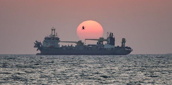 El sol se pone sobre un barco frente a la costa de Dubái.