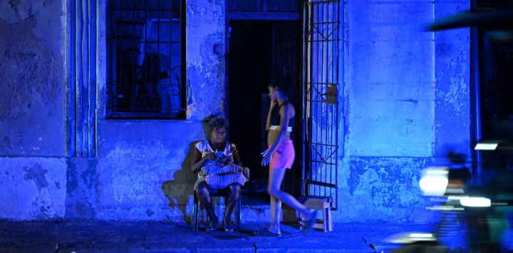 Una mujer revisa su teléfono celular durante un apagón en el barrio Centro Habana de La Habana, Cuba.