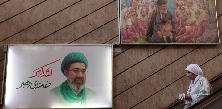 Una mujer usa una escalera mecánica bajo una foto del líder supremo de Irán, el ayatolá Mojataba Khamenei (izquierda), en una estación de metro de Teherán. El asesor militar del líder supremo de Irán advirtió sobre más ataques con misiles y drones si Estados Unidos reanudaba sus ataques contra Irán. La advertencia se produjo tras los ataques estadounidenses contra un petrolero iraní y contra la isla iraní de Qeshm, lo que provocó ataques de represalia contra Kuwait y Bahréin.