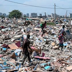 Jóvenes caminan sobre escombros en busca de diversos objetos tras la destrucción del precario barrio de Zimbabwe durante una operación de desalojo en el barrio de Port-Bouet en Abidjan. | Foto:SIA KAMBOU / AFP