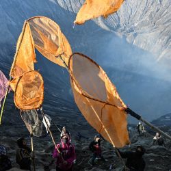 Los aldeanos recogen las ofrendas que los devotos hindúes de la comunidad Tengger arrojan al cráter del monte Bromo durante el festival Yadnya Kasada cerca de Probolinggo, provincia de Java Oriental, Indonesia. | Foto:JUNI KRISWANTO / AFP