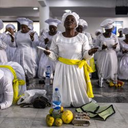 Un fiel se arrodilla en oración junto a los objetos de acción de gracias durante un servicio religioso en la sede internacional de la Iglesia Celestial de Cristo en el barrio de Ketu, Lagos. | Foto:OLYMPIA DE MAISMONT / AFP