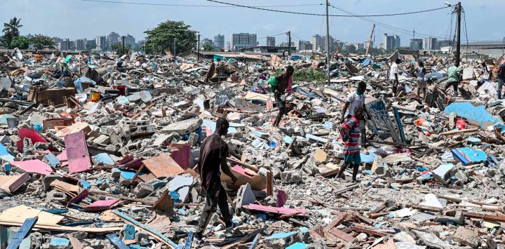 Jóvenes caminan sobre escombros en busca de diversos objetos tras la destrucción del precario barrio de Zimbabwe durante una operación de desalojo en el barrio de Port-Bouet en Abidjan.