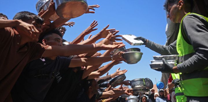 Palestinos desplazados se reunieron para recibir comidas calientes distribuidas por un comedor social en Khan Yunis, al sur de la Franja de Gaza. Esta distribución de alimentos se produjo en medio de la continua escasez de suministros alimenticios causada por los ataques israelíes y las restricciones a la entrada de ayuda humanitaria en la Franja de Gaza.