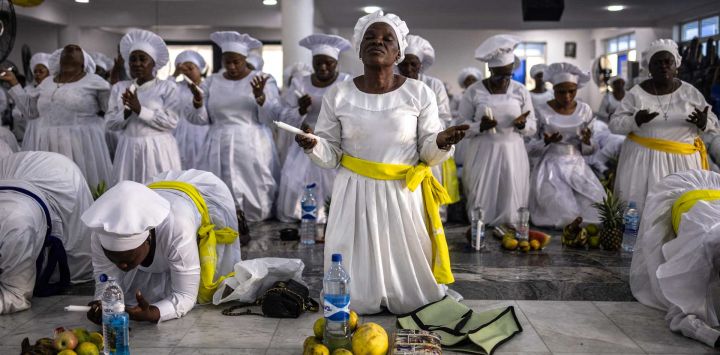Un fiel se arrodilla en oración junto a los objetos de acción de gracias durante un servicio religioso en la sede internacional de la Iglesia Celestial de Cristo en el barrio de Ketu, Lagos.