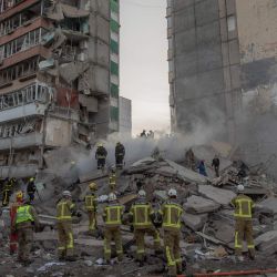 Los equipos de rescate trabajan en un edificio residencial parcialmente destruido tras los ataques con drones y misiles rusos en Kiev, en el contexto de la invasión rusa de Ucrania. | Foto:ROMAN PILIPEY / AFP