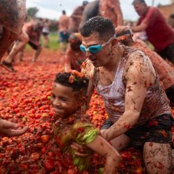 Un hombre agarra a un niño durante el XVI Festival de la Lucha del Tomate, conocido como "Tomatina", en Sutamarchan, departamento de Boyacá, Colombia. | Foto:ESTEBAN VEGA LA-ROTTA / AFP
