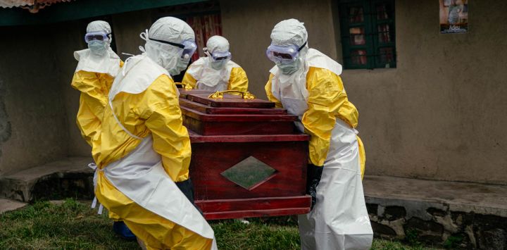 Miembros de un equipo de la Cruz Roja Congoleña, con equipo de protección personal, transportan el ataúd de una mujer presuntamente fallecida por la enfermedad del virus del Ébola, antes de su entierro seguro en su casa en Bunia. La UE anunció el envío de 100 toneladas de ayuda humanitaria a una zona de difícil acceso en el este de la República Democrática del Congo, afectada por un brote de Ébola.