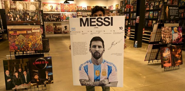 Un vendedor posa con una pancarta del delantero argentino Lionel Messi en una tienda cerca del Compass Minerals PerformanceCenter, el centro de entrenamiento de la selección argentina de fútbol, en Kansas City, Missouri. Kansas será sede de seis partidos de fútbol durante la Copa Mundial de la FIFA 2026.