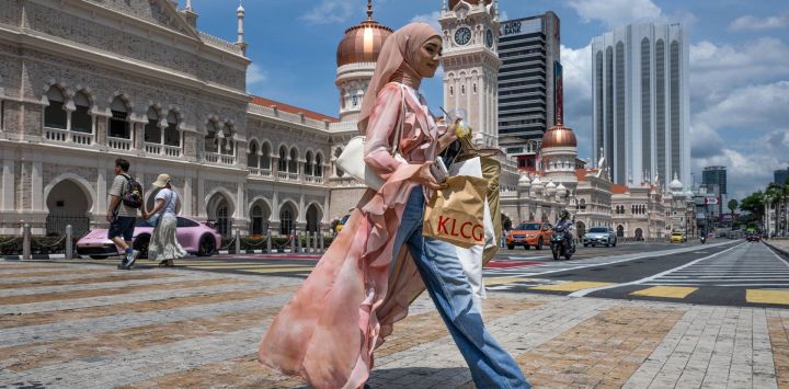 Una mujer cruza la calle frente al edificio Sultan Abdul Samad, cerca de la plaza Merdeka en Kuala Lumpur, Malasia.