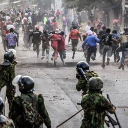 Manifestantes buscan refugio durante enfrentamientos con agentes de la policía keniana en una protesta contra un controvertido centro de cuarentena para el ébola, construido por Estados Unidos en la base aérea de Laikipia, en Nanyuki. Varios kenianos fueron arrestados en las últimas protestas contra la construcción de un centro de cuarentena para ciudadanos estadounidenses en una ciudad turística. | Foto:LUIS TATO / AFP