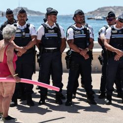 Un bañista habla con los agentes de policía reunidos en el paseo marítimo de la playa de Catalans durante la rueda de prensa de la prefectura para anunciar las medidas de seguridad implementadas en las playas de Marsella, en el sureste de Francia. | Foto:Thibaud Moritz / AFP