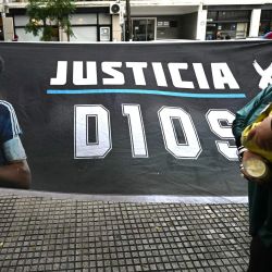 Una mujer pasa junto a una pancarta que muestra al legendario futbolista argentino Diego Maradona y exige justicia frente al tribunal antes de la audiencia sobre su muerte en San Isidro, provincia de Buenos Aires, Argentina. | Foto:LUIS ROBAYO / AFP