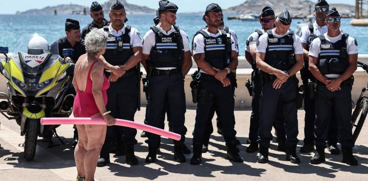Un bañista habla con los agentes de policía reunidos en el paseo marítimo de la playa de Catalans durante la rueda de prensa de la prefectura para anunciar las medidas de seguridad implementadas en las playas de Marsella, en el sureste de Francia.