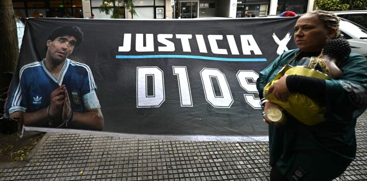 Una mujer pasa junto a una pancarta que muestra al legendario futbolista argentino Diego Maradona y exige justicia frente al tribunal antes de la audiencia sobre su muerte en San Isidro, provincia de Buenos Aires, Argentina.