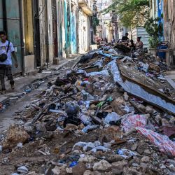 Varias personas caminan junto a montones de basura en una calle de La Habana, Cuba. | Foto:YAMIL LAGE / AFP