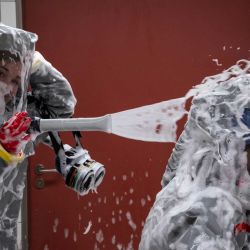 Dos enfermeras con sus EPI (Equipos de Protección Individual) utilizan un desinfectante espumoso en una cámara de descontaminación tras recibir a un paciente con una enfermedad altamente infecciosa como el ébola, durante una simulación en la sala de aislamiento especial del Departamento de Enfermedades Infecciosas del hospital Charité Virchow de Berlín. El hospital alemán dio de alta a un estadounidense que contrajo el ébola en la República Democrática del Congo, tras 17 días de tratamiento antiviral y atención médica que lo curaron de la infección, a menudo mortal. | Foto:JOHN MACDOUGALL / AFP