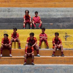 Jóvenes iraníes se sientan en las tribunas durante una sesión de entrenamiento en un centro de fútbol en Teherán. | Foto:ATTA KENARE / AFP